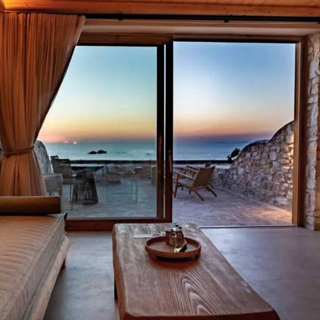 a living room with a sofa and a table with a view of the ocean at sunset at Mythic Paros