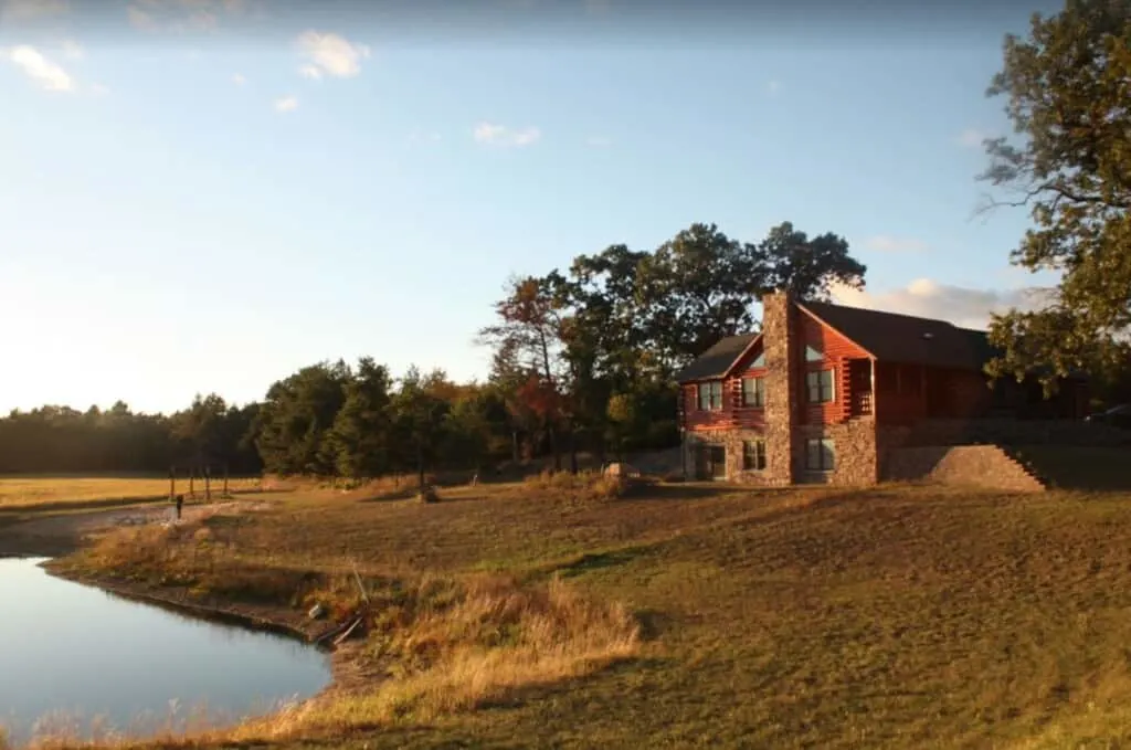 Discover the best luxury cabin rentals in wisconsin, cabin in north wisconsin with private swim pond surrounded by rolling fields and trees at sunset