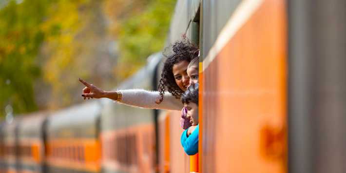 Best fall vacation spots in Wisconsin, close up shot of some people looking out of the window of a long orange train