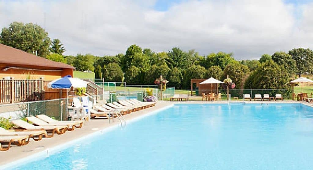 pool view of Christmas Mountain Village Resort filled with empty pool chairs and trees tat the back