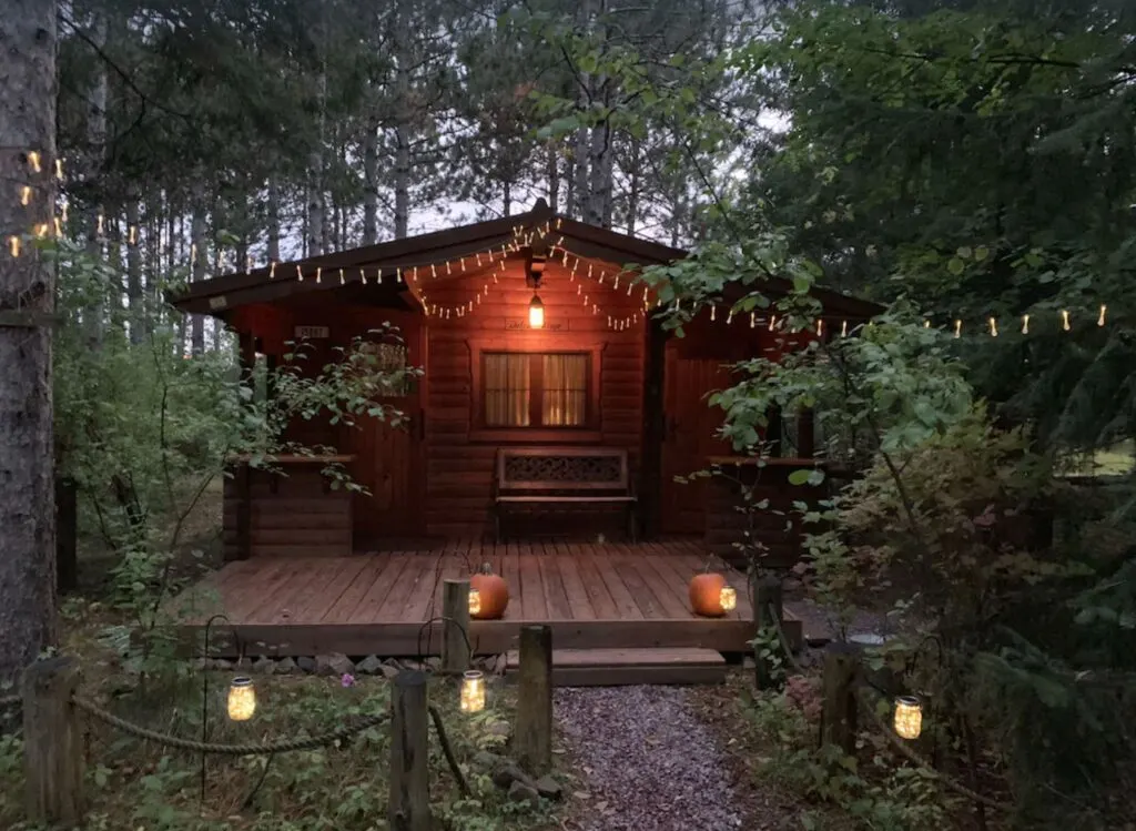 romantic weekend getaways wisconsin, secluded cabin in wisconsin with lights and surrounded by a lot of green bushes and trees