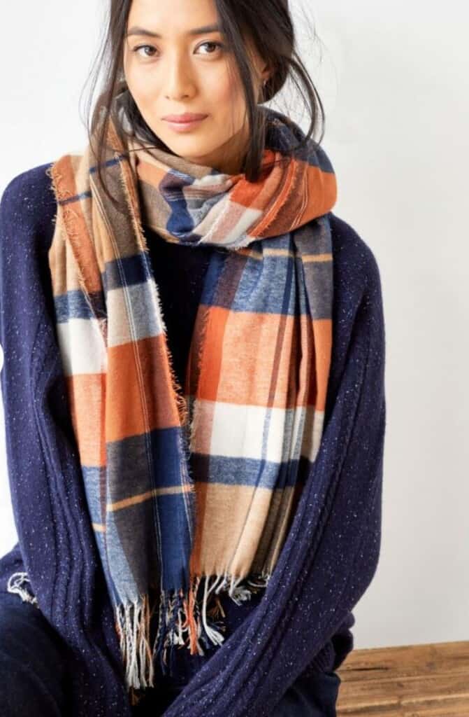 amazing recycled clothes company, asian woman wearing navy fleece and chunky checkered orange, white and blue scarf