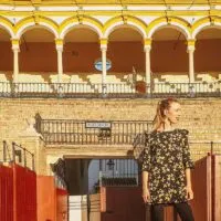 a woman posing in front of a building gate with a balcony, andalusia travel blogger in spain, paulina