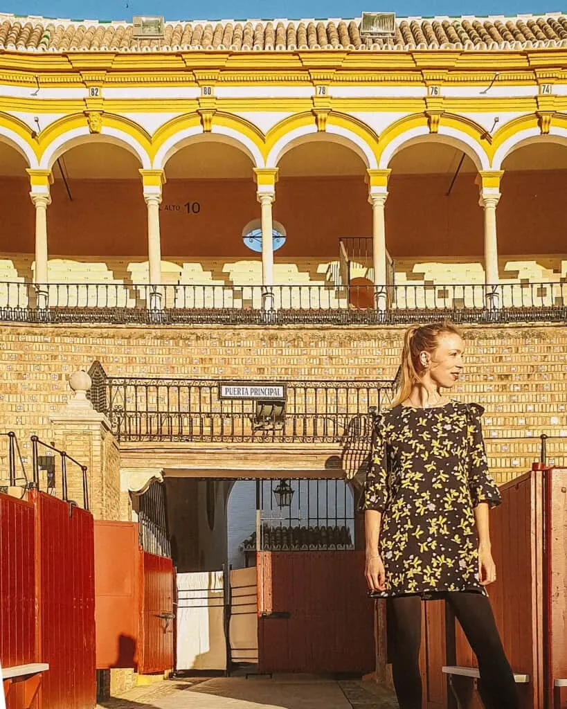 a woman posing in front of a building gate with a balcony, andalusia travel blogger in spain, paulina