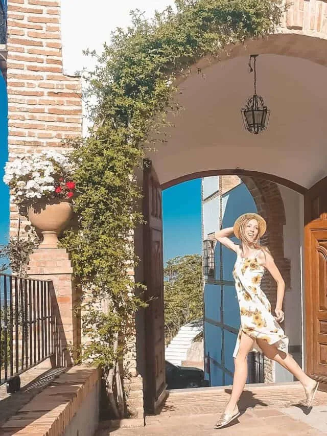 a gril on a sunflower dress jumping for a pose by a door