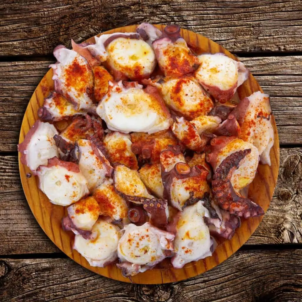 a plate of food with octopus slices on a wooden table