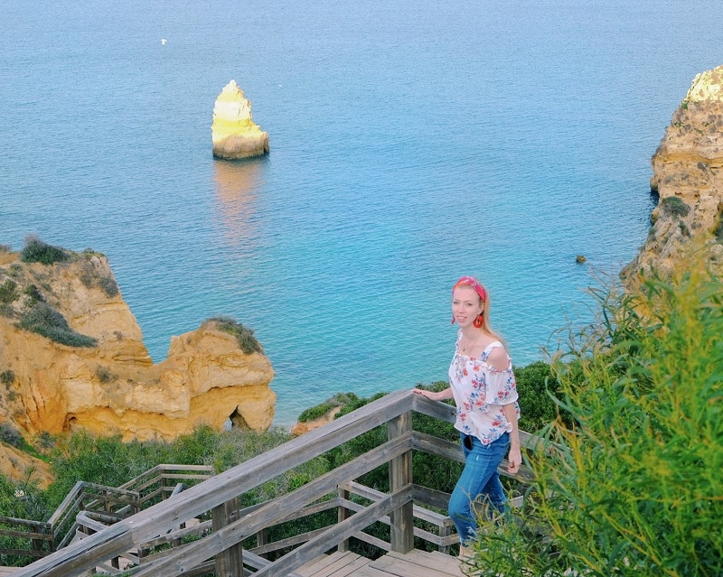 a woman walking on a walkway near a beach with a beach on a view