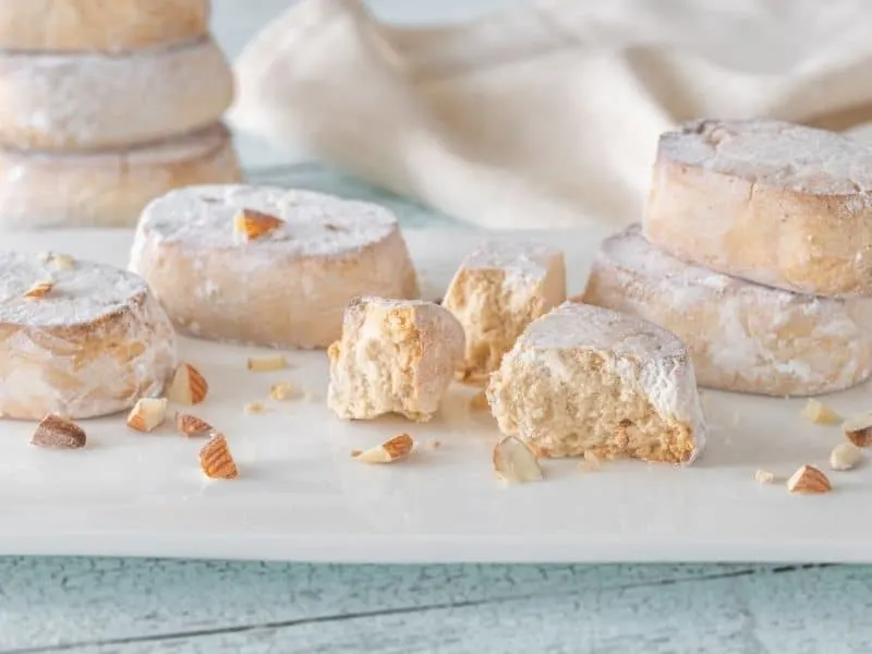 polvoron, spanish shortbread, pieces covered in flour on a white plate