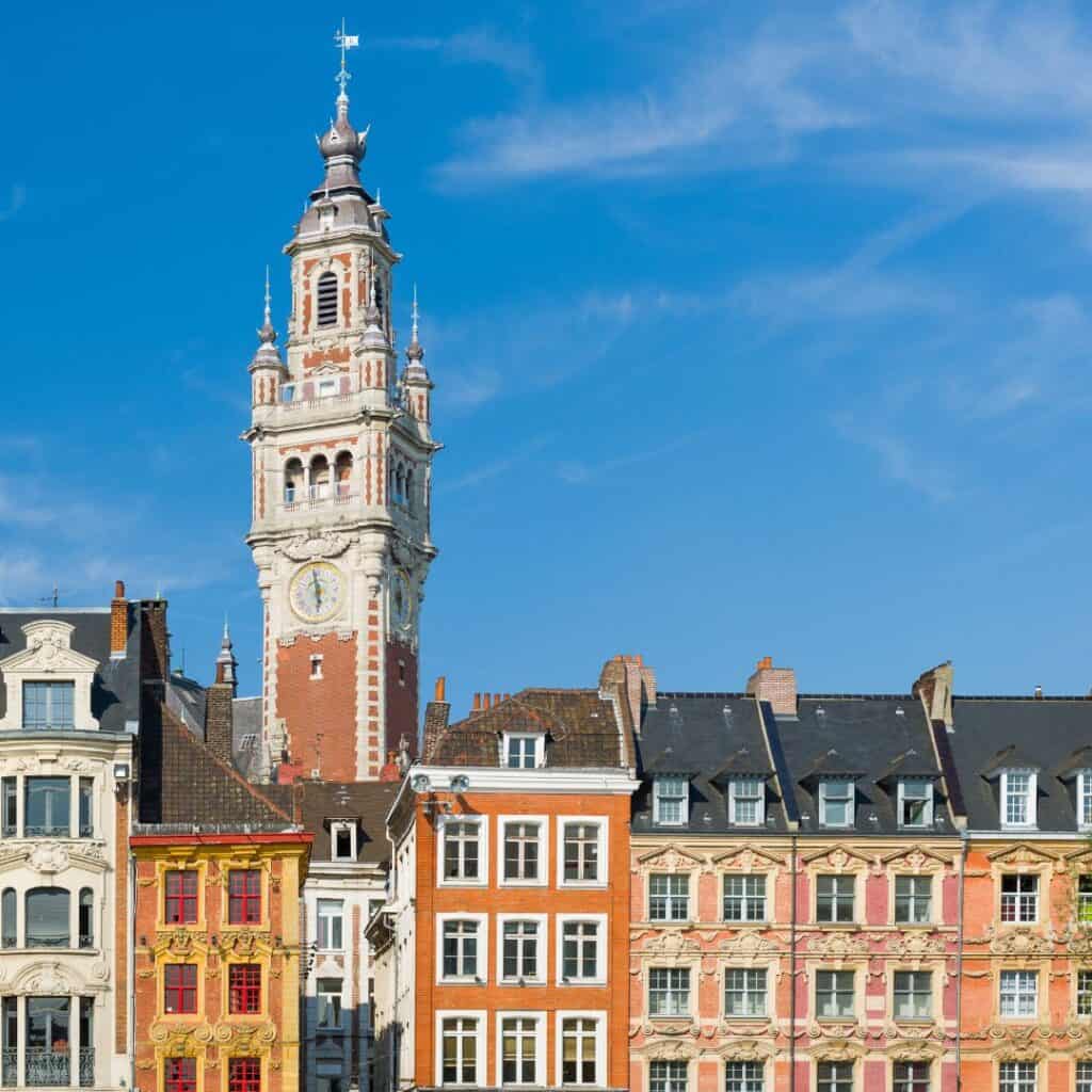 a clock tower with buildings below under a blue sky