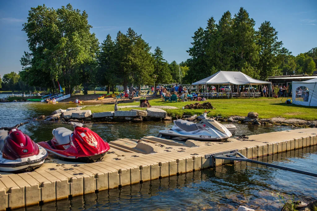 door county resorts on the water, pier with jet skis and tent in background with lots of activity 