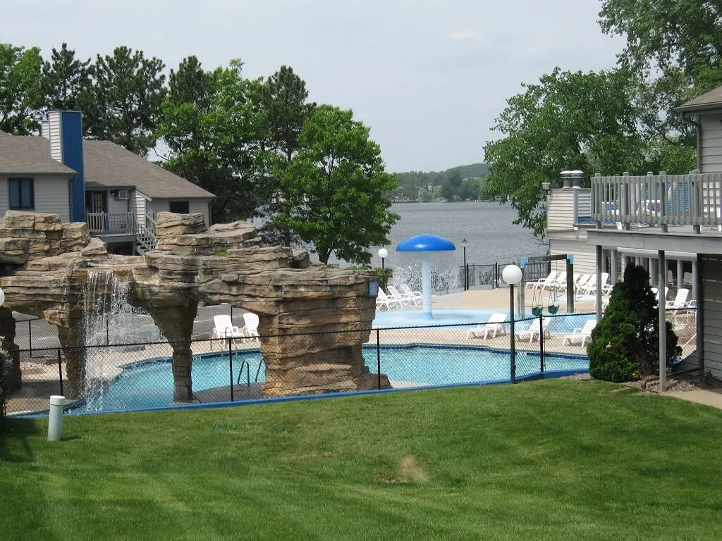 best vacation spots in wisconsin for families, view of pool area with rock formation and lake in background