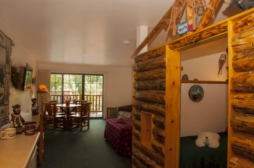 wisconsin dells kid friendly resorts, large room with bed, table, balcony and sleeping alcove for kids with bear plushie