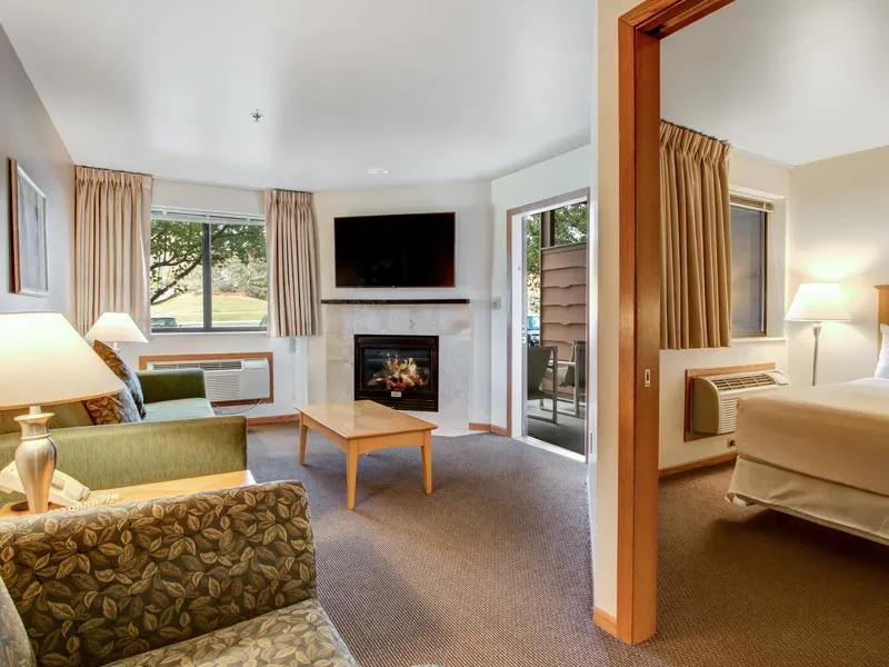 family friendly resorts on lake geneva, large suite with bed, living room area with fireplace and balcony at Timber Ridge Lodge and Waterpark at Grand Geneva
