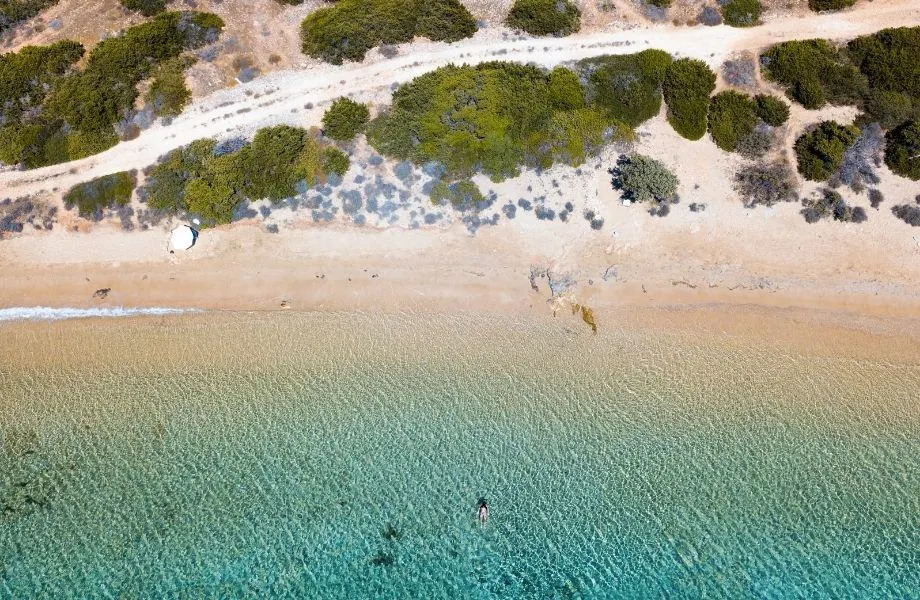 nude beach Paros, aerial view of person swimming in the clear waters of Lageri Beach