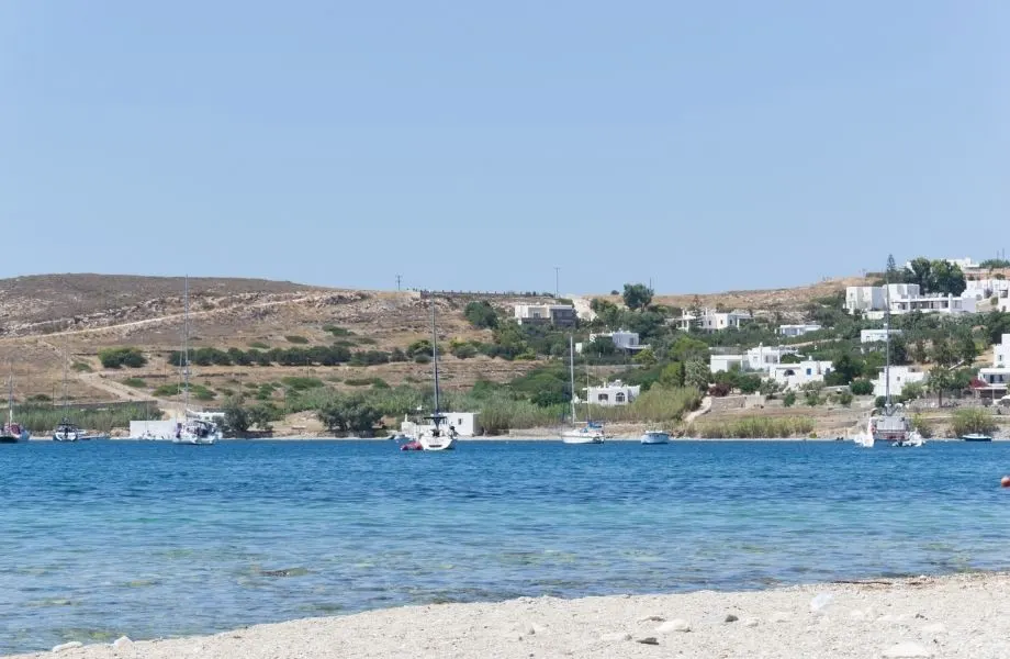 Must See Beaches in Paros Greece, Livadia Beach with boats on the water and white square homes in the hills