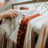 best sustainable vegan clothing brands, person pulling a shirt of the rack