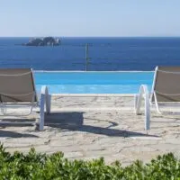 Best Resorts in Paros for Every Budget, two beach chairs overlooking pool and ocean at Archipelagos Resort & Villas