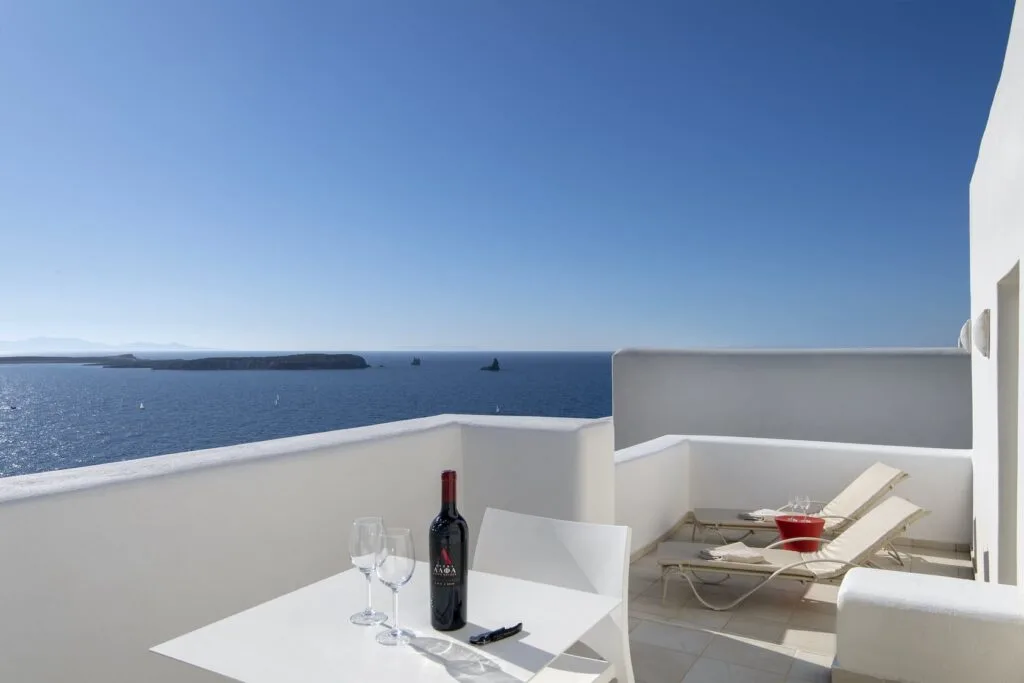 top hotels in Paros, balcony with deck chairs and table with wine bottle and glasses overlooking ocean