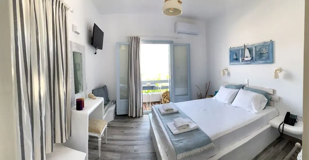 boutique hotels Greece, room with bed, desk, seating area and boat art above bed, balcony overlooking garden