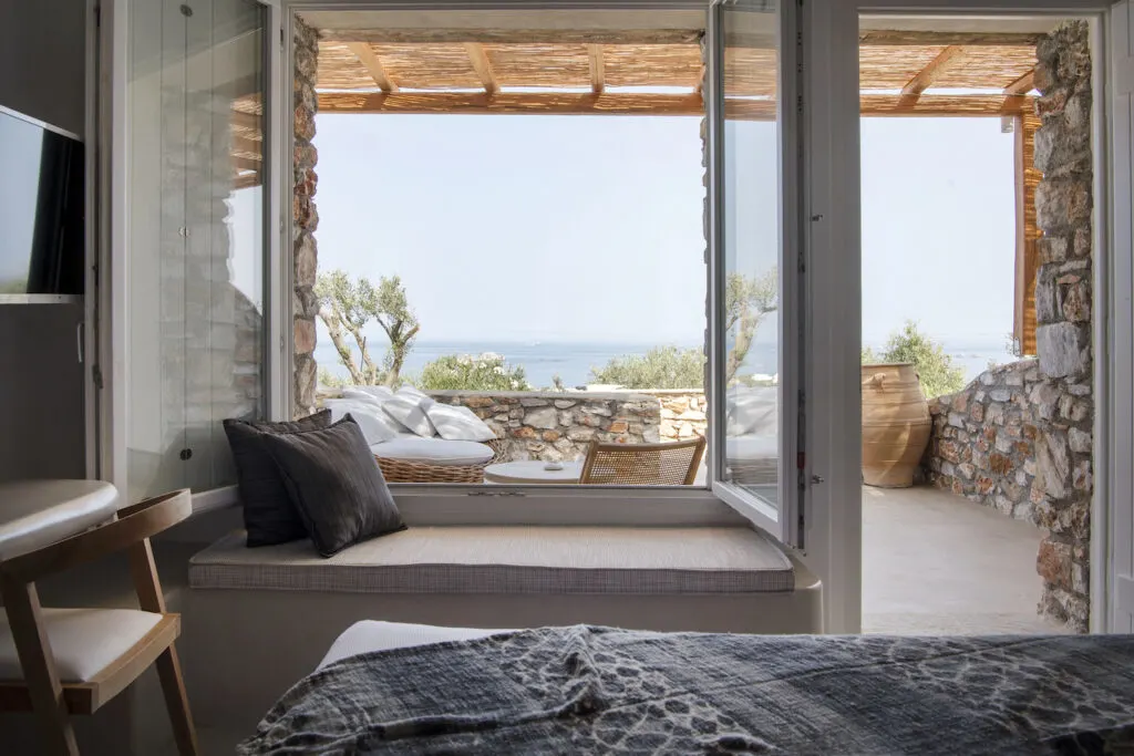 luxury resorts in Paros Greece, room with bed, desk, and large outdoor seating area at the adults only Mythic Exclusive Retreat