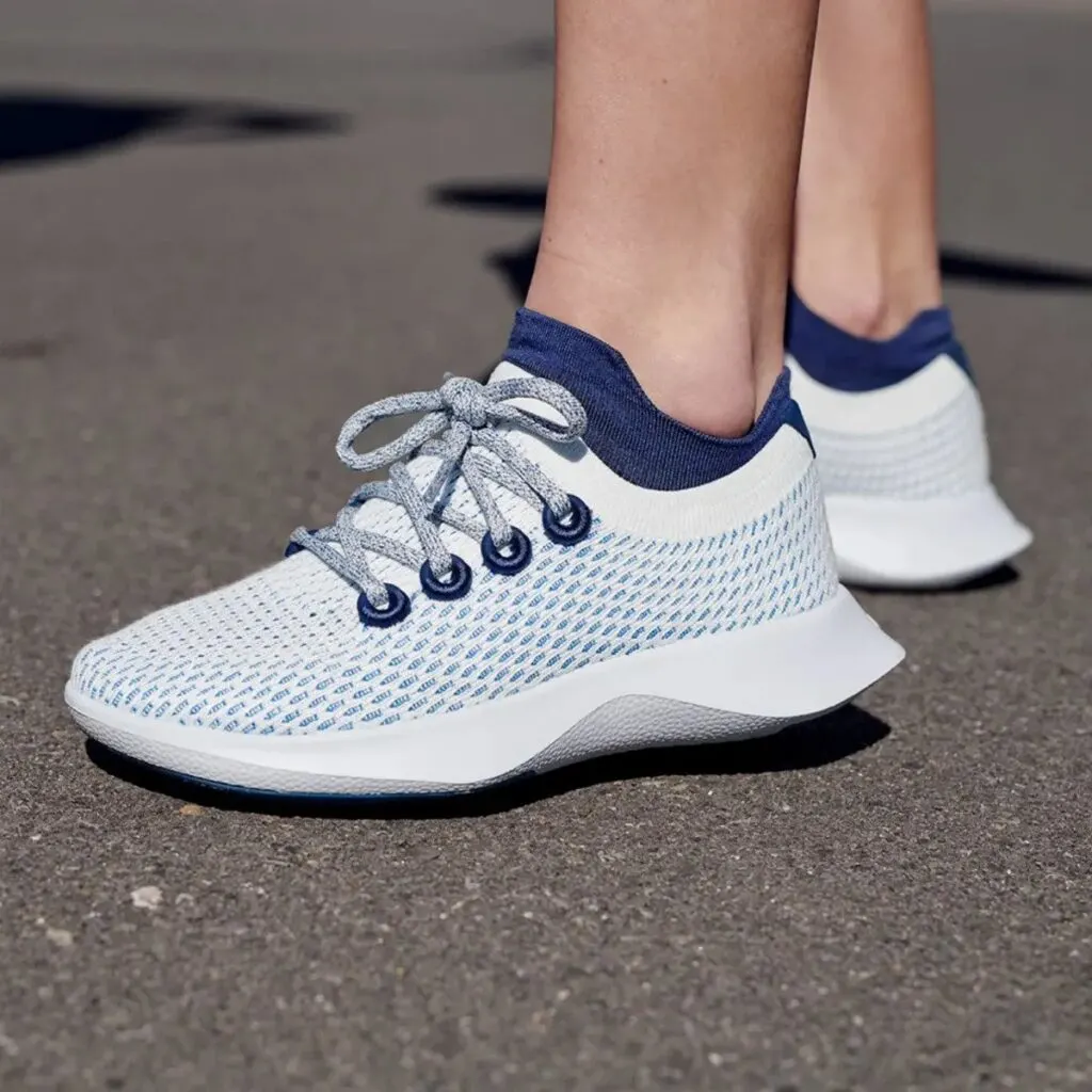 sustainable gifts for Christmas, feet of person wearing white Allbirds Sneakers with blue mesh highlights