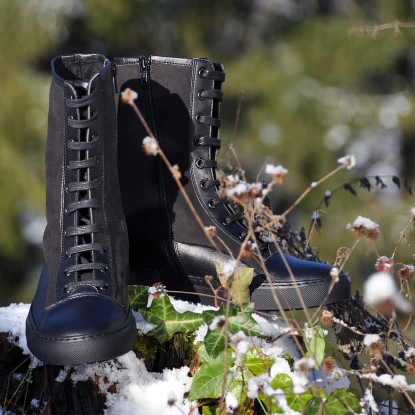 european eco-friendly boots for men and women, black lace up winter boots resting on snow