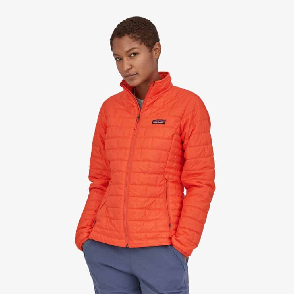 brands with the best sustainable winter coats, woman wearing orange puffer coat
