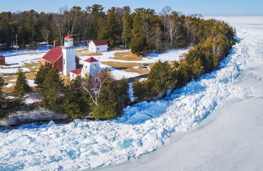 winter weekend getaways in Wisconsin, Sherwood Point Lighthouse surrounded by frozen lake and a ring of lush green trees