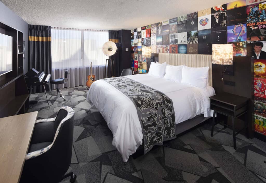 pet friendly hotels in Milwaukee, Wisconsin, hotel room with bed, keyboard, guitar and a wall covered in record album covers