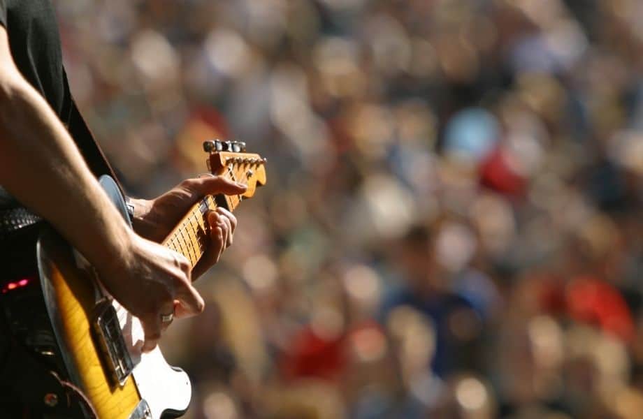 fun date ideas in milwaukee, person playing electric guitar in front of large, blurry crowd