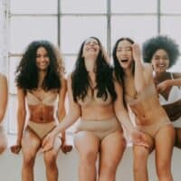 best sustainable underwear brands, group of women in underwear and bra hanging out and laughing