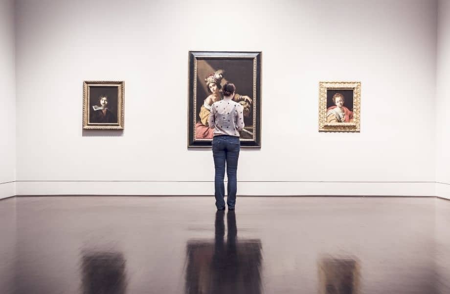 woman standing in front of paintings in a museum