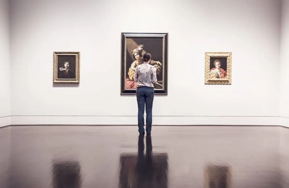 woman standing in front of paintings in a museum