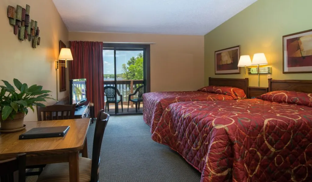 hotel room with two beds and balcony overlooking lake