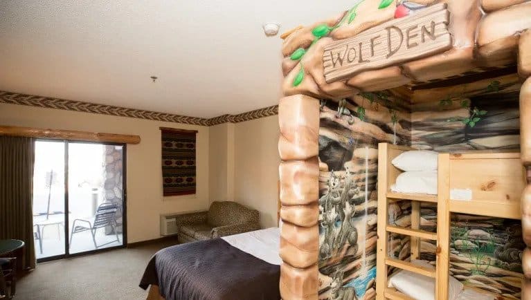 where to stay in Wisconsin Dells for families, room with bunk beds in themed wolf den area, double bed, sofa chair and balcony