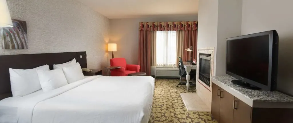 best couples resorts in Wisconsin Dells, hotel room with bed, sofa chair, tv, desk and fireplace