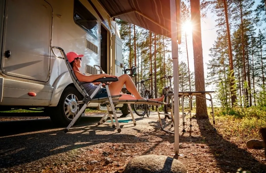 where to go camping in wisconsin dells, woman relaxing in a chair outside her rv camper enjoying nature