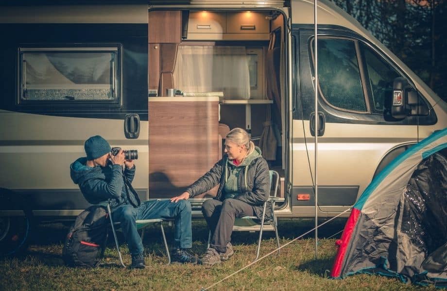 best Wisconsin campsites, man and woman sat outside rv camper near a tent, man taking photo of woman