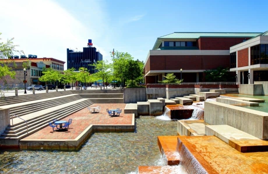 park and fountain in downtown sheboygan with stairs, chairs and tables in the middle and buildings at the back