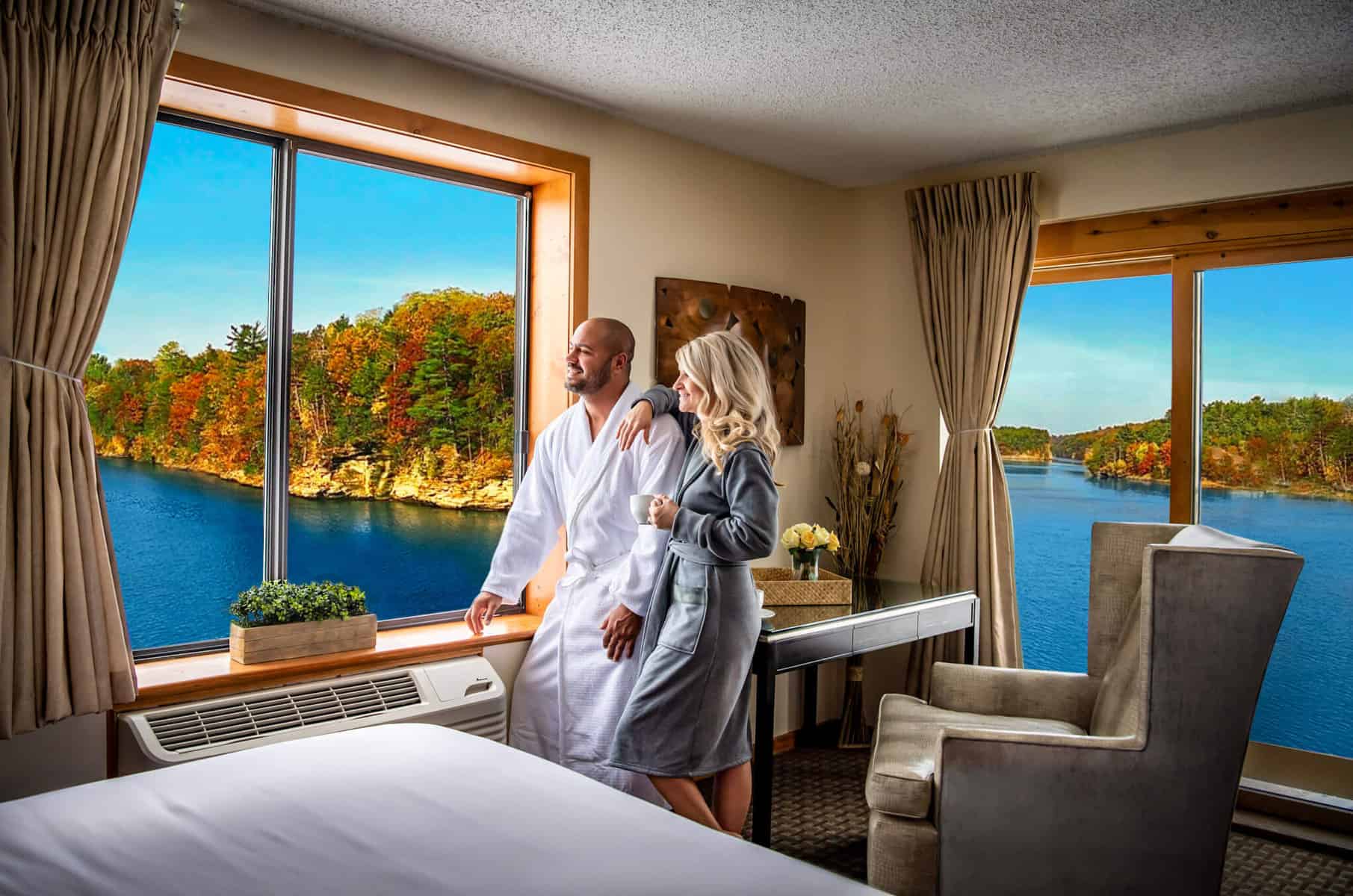 couple in bathrobes looking out of windows at the lake during autumn in romantic resorts in wisconsin