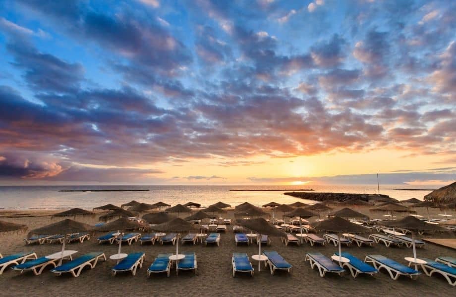 Best hotels in Costa Adeje, Tenerife, rows of beach chairs and umbrellas on beach at sunset