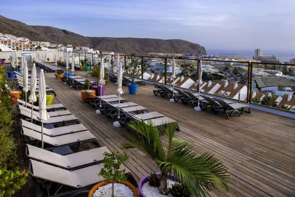 Best hotels in Costa Adeje for families, outside lounge area on wooden balcony with view of Costa Adeje, the ocean and mountains
