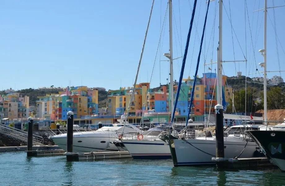 Amazing places to visit in Albufeira, boats docked on marina with colorful buildings in background