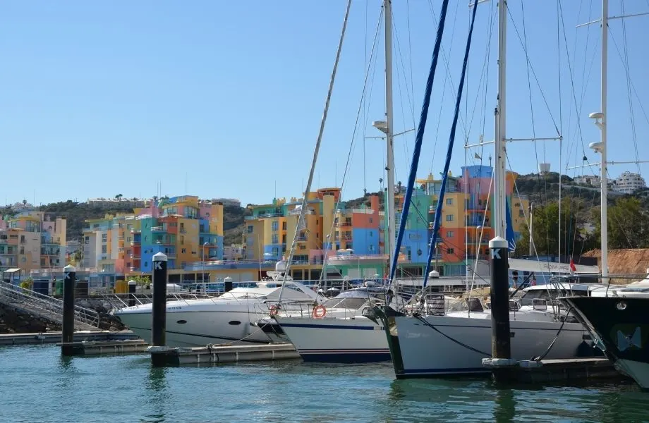 day trips from Lagos Portugal, boats docked on marina with colorful buildings in background