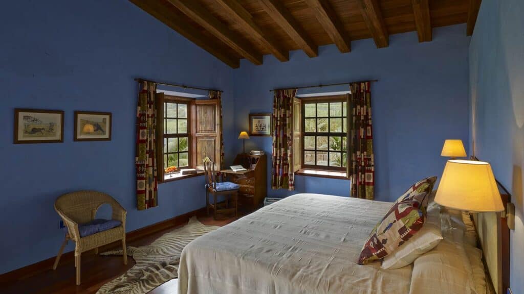 Secluded spa hotels in Tenerife, hotel room painted blue with bed, chair, desk and large windows looking out at nature