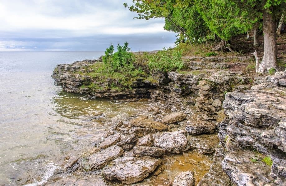 rocky cliffs with many boulders having fallen into surrounding water in door county