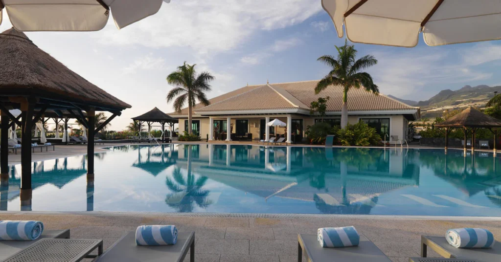 Best adult-only spa hotels in Tenerife, outdoor pool area and deck chairs with rolled up towels on each one, view of mountains in the distance