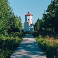 best things to do in Door County in March, wooden boardwalk surrounded by trees leading up to small red and white lighthouse