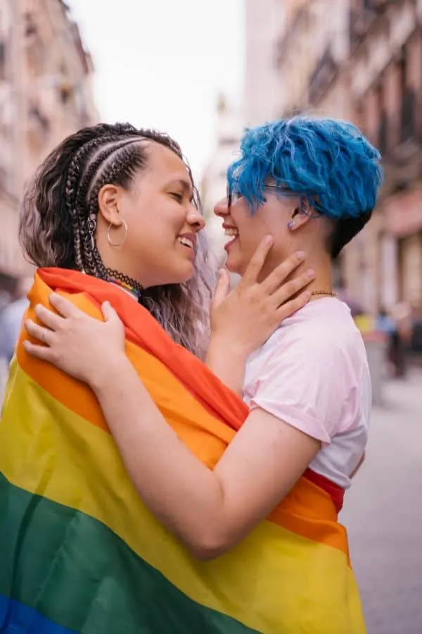 a lesbian couple looking at each other wrapped around a pride flag