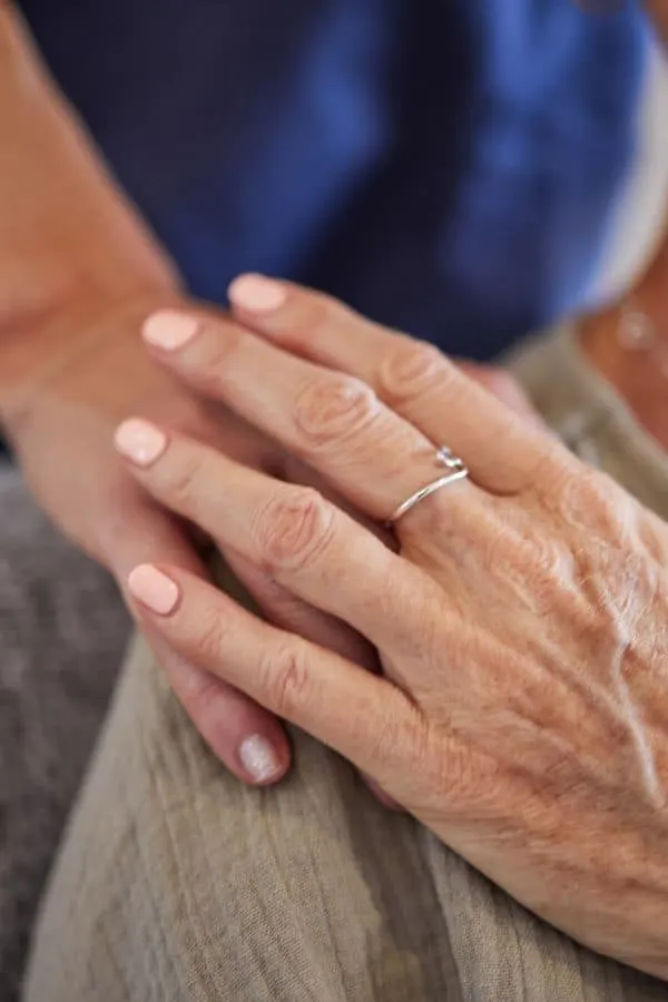 the wife's hand is reaching out for her husband's hand that is on her shoulder